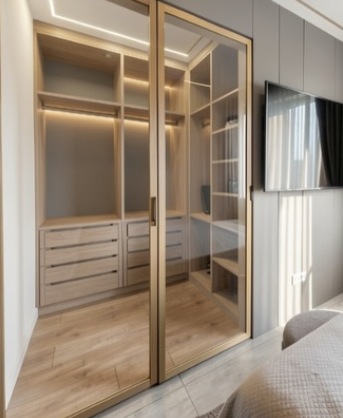 Closet planejado com portas de vidro, perfis metálicos e iluminação interna